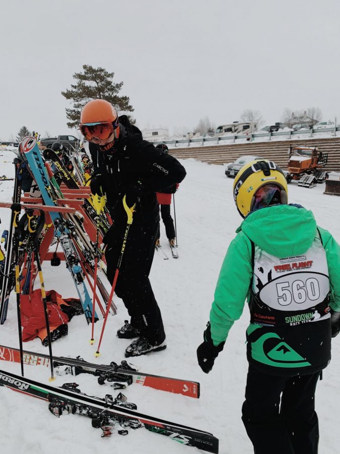 Nick Obbink, (Senior HS), Fin Newlin, (OLG), go to put their skis on before they race. Despite the age difference, Obbink and Newlin never fail to hype each other up before sending them down the course.