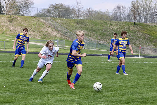 Brant Perry, '22, dribbles the ball past the defenders in a game against Assumption. Perry will be one of the leaders on the team this year, as he enters his senior season. 